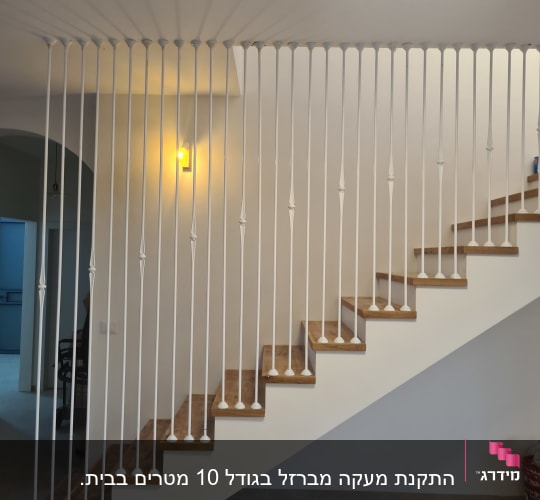 מעקה מתכת לבן לאורך מדרגות עץ